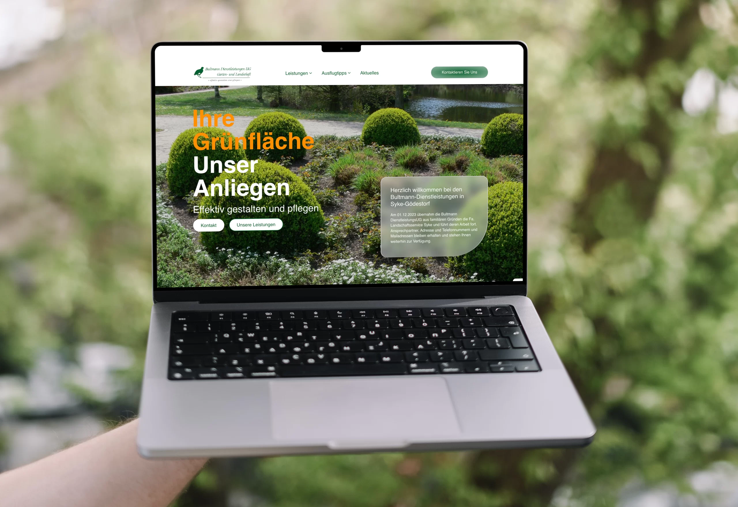 Eine Hand hält ein MacBook Pro, das eine Website mit Landschaftsgestaltung zeigt.