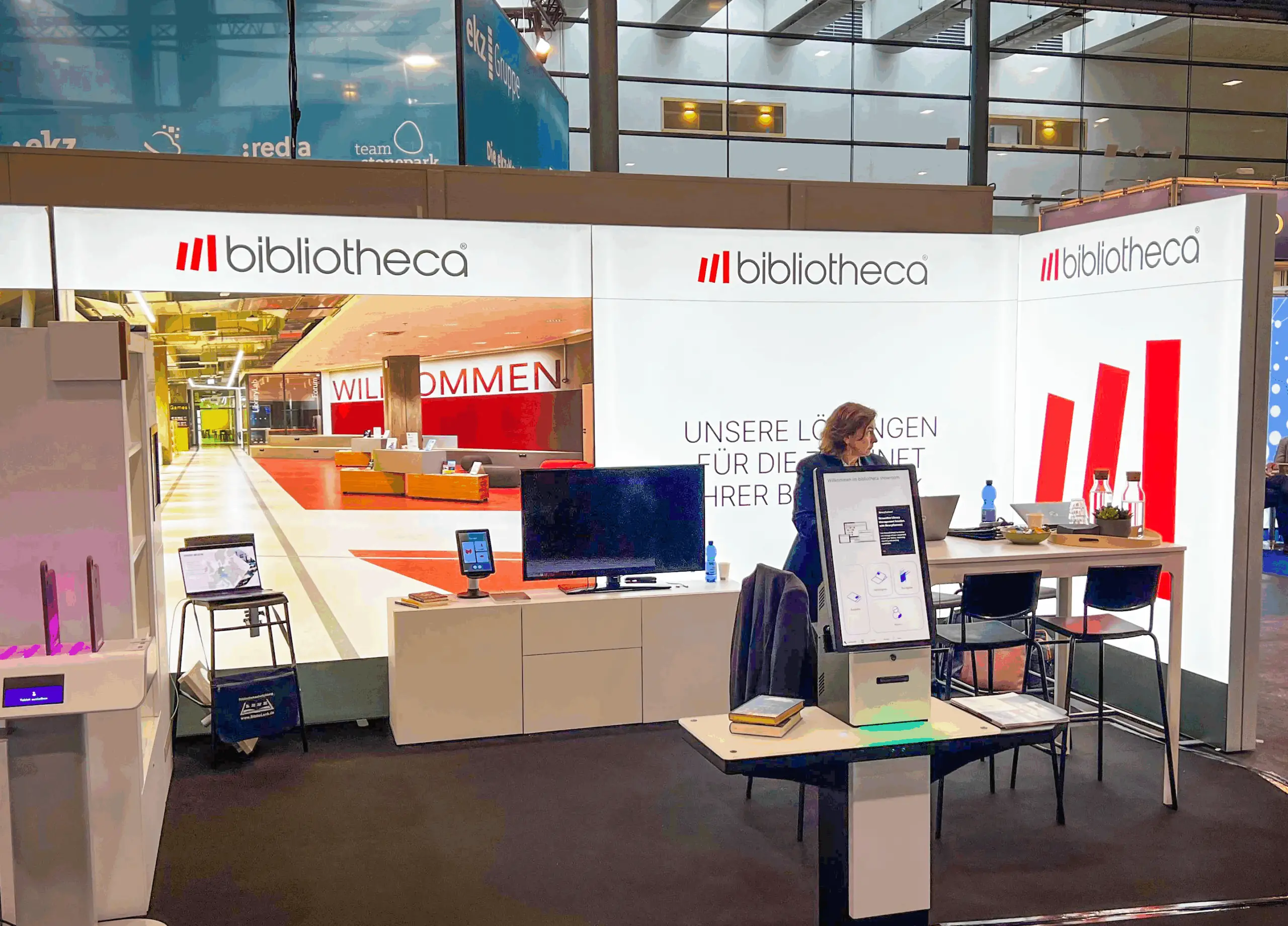 Messestand von bibliotheca mit einem Empfangstresen und Displays auf einer Veranstaltung.