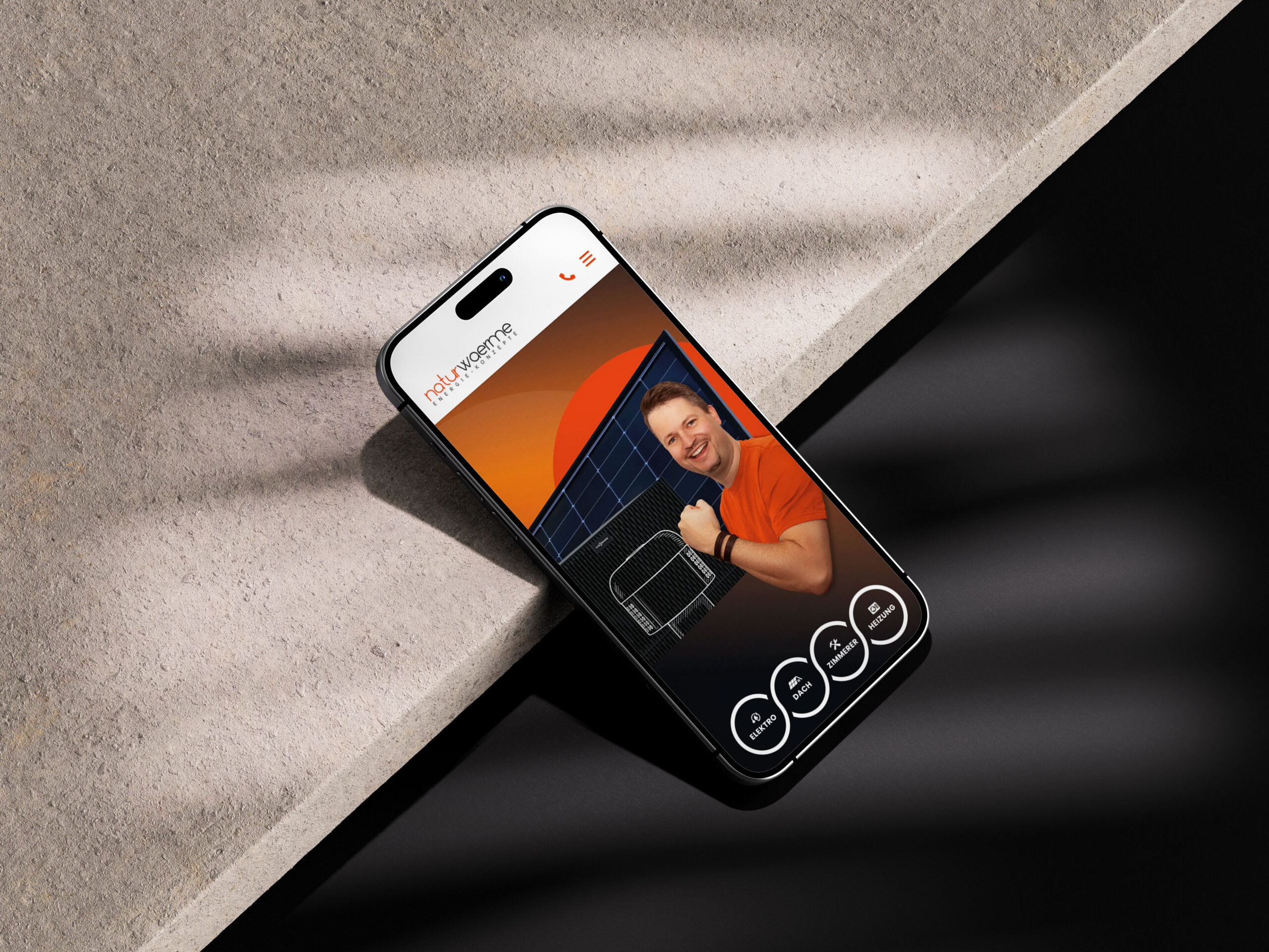 Smartphone mit einer App-Oberfläche, die einen Mann in einem roten Shirt zeigt, der vor einem Solarpanel steht.