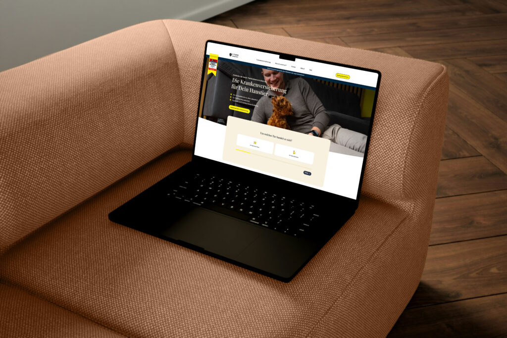 Schwarzer MacBook auf einem Sofa mit einem offenen Bildschirm, der eine Website zeigt.