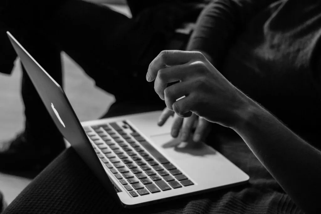 Eine Hand, die auf der Tastatur eines MacBook Pro tippt, in Schwarz-Weiß gehalten.