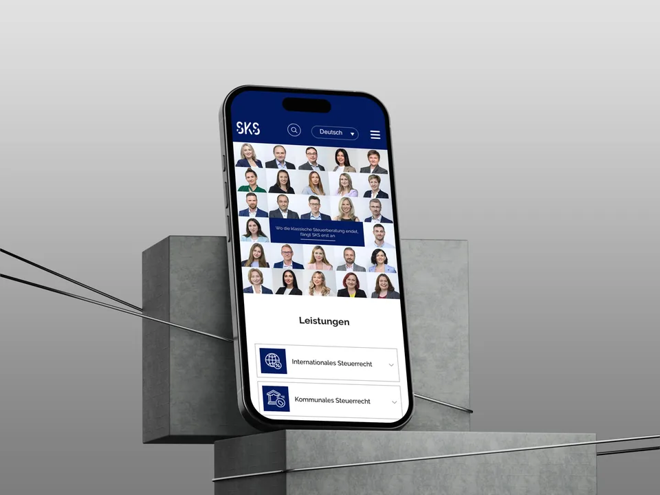 Smartphone auf grauen Betonblöcken mit der mobilen SKS-Website: Porträt-Mosaik in fünf Spalten, darunter die Leistungen als Liste mit blauen Icons.